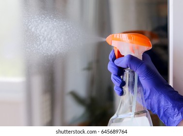 Woman cleaning a window with cleaning sprayer.