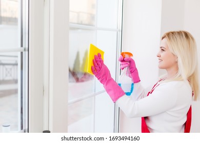 Woman cleaning windows at home with detergents cleaner - Shutterstock ID 1693494160