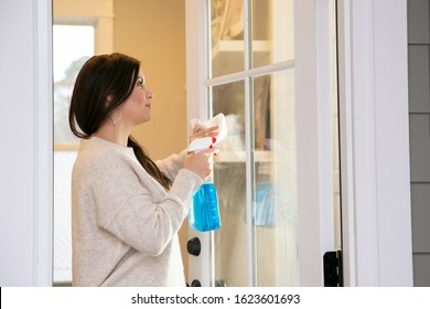 Woman Cleaning The Windows To The Outside Of A Front Door