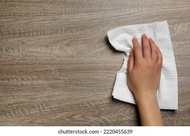 Woman Cleaning Wooden Table With Paper Towel, Top View. Space For Text