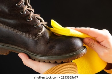 A woman cleans brown nubuck boots on a black background, wipes the dust with a yellow shoe rag. - Powered by Shutterstock