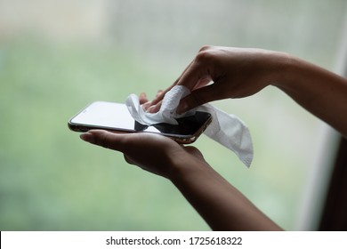 The Woman Cleans The Cell Phone With A Wet Wipe Napkin Stock Photo