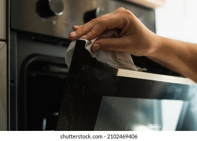 A Woman Cleans A Dirty Oven With A White Napkin. Horizontal View.