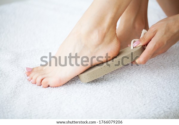 Woman cleans the\
heel of the foot with\
pumice