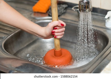 woman cleans plunger with clogged sink, close up