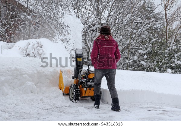A woman\
cleans the winter snow with the snow\
mills