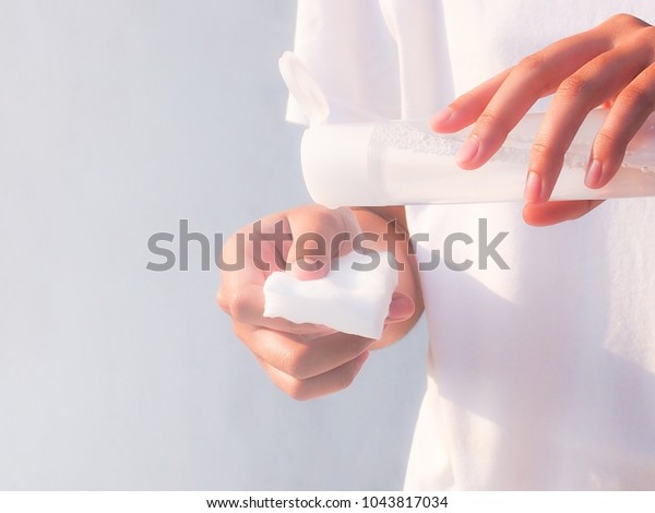 Woman with cleansing toner bottle and cotton  to\
clear skin.