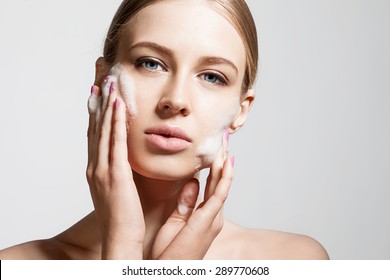 Woman Clears A Face Skin Foam On A Gray Background