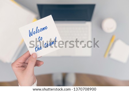 Woman clerk sitting holding note paper sticker with welcome to the team phrase. Business concept. Concept. 