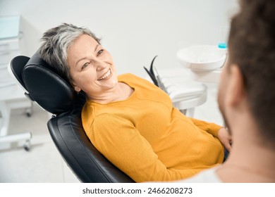 Woman client in her 50 looking at doctor stomatologist and smiling - Powered by Shutterstock