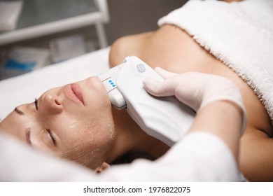 Woman Client Lying In Beauty Salon Room, Receives Ultrasound Smas Non-surgical Face Lift By Professional Beautician Doctor, Hand Holding Ultrasonic Hardware Cosmetology Device For Facial Treatment