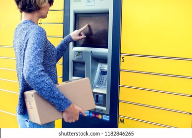 Woman client using automated self service post terminal machine or locker to deposit the parcel for storage,