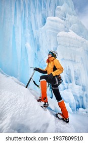 Woman Climber In Orange Jacket With Ice Axe Near Frozen Waterfall In The Mountains In Almaty, Kazakhstan