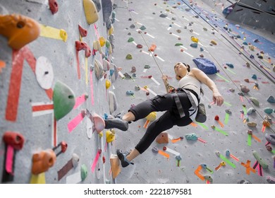 Woman climbing indoor rock wall - Powered by Shutterstock