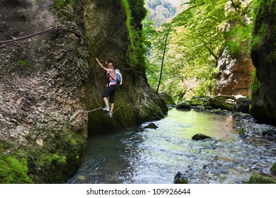 Woman Climbing Mountain Wall Over A River In A Canyon