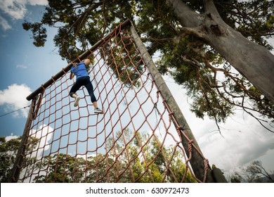 Woman climbing a net during obstacle course in boot camp - Powered by Shutterstock