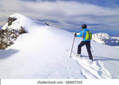 Woman climbing on touring skis in sunny winter day, Les Deux Alpes, France