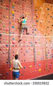 Woman Climbing Up Rock Wall At The Gym