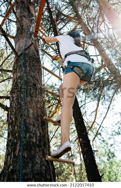 Woman\
climbing a rope ladder outdoors in team\
building