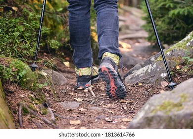 Woman Climbs In Hiking Boots In Outdoor Action. Top View Of Boot On The Trail. Close-up Legs In Jeans And Sport Trekking Shoes On Rocky Stones Of Mountain Forest. Local Travel 