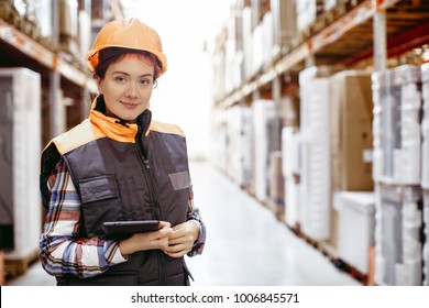 Woman with a clipboard in her hands is checking inventory levels in a warehouse. Smiling girl scrolling on digital tablet in a large warehouse time delivery concept photo.