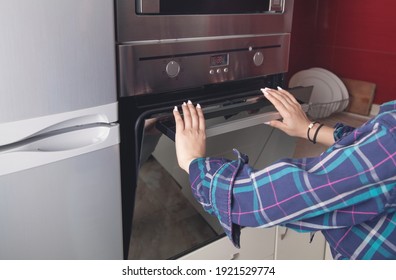 Woman Close Oven Door In The Kitchen.