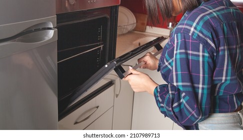 Woman Close Oven Door In The Kitchen.