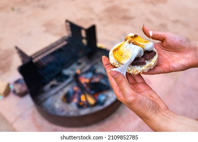 Woman Closeup Hand Holding Messy Sticky Roasted Marshmallows Smores With Chocolate Rice Cake Cracker By Fire Pit In Campground Campfire Grill