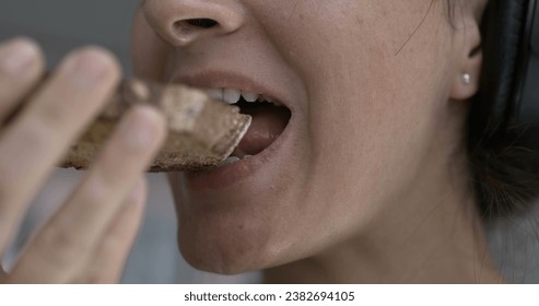 Woman close-up mouth taking a bite of toast bread . Person eating carb food