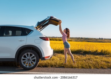 woman closing car trunk parked at roadside copy space