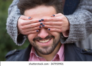 Woman Closing His Man's Eyes For Guessing On The Street. Handsome Man Dreaming About Real Surprise.