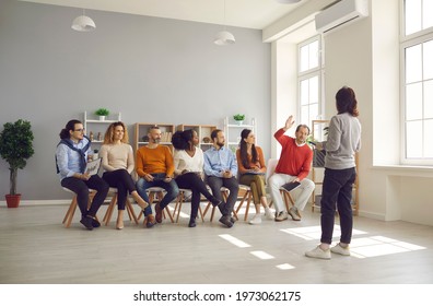 Woman Coach Presenting Business Conference Training For Diverse Multiethnic Corporate Staff In Coworking Space Office. Adult Man Sitting With Raised Hand Ready To Answer. Business School Class