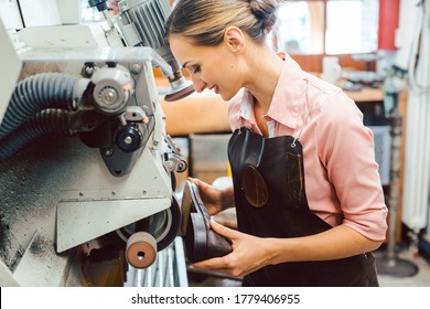 Woman cobbler working on machine in her shoemaker workshop adjusting the settings - Powered by Shutterstock