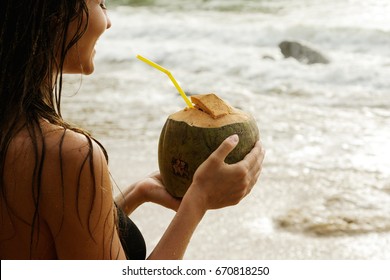 Woman with a coconut drink on the beach