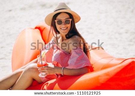 Woman with coctail in hat at the beach