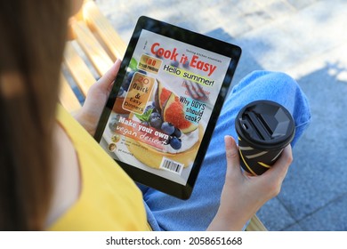 Woman With Coffee Reading Online Magazine On Tablet Outdoors, Closeup