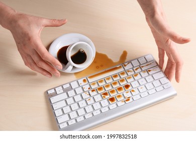 Woman with coffee spilled over computer keyboard at wooden table, above view