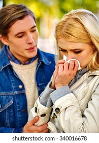 Woman With Cold Rhinitis On Autumn Outdoor. Fall Flu Season. Man Looks With Compassion On Suffering Of Loved One. Autumn Park Outdoor.