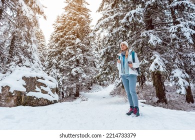 Woman In Cold Snow Hiking Down A Path Thru The Woods