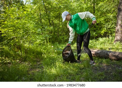 Woman collecting garbage with trash picker in the woods, copy space - Powered by Shutterstock