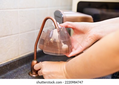 A Woman Collects Water In Water Tank Of Portable Hand Steamer For Clothes. Steam For Ironing Clothes. Household Appliances For The Home.