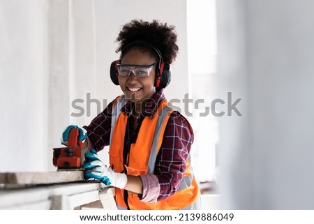 A woman of color is working happily to build a house.