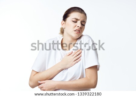 A woman in a colored T-shirt touches herself with her health problems