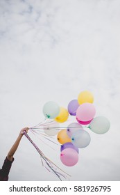 Woman with colorful balloons outside blue sky background.