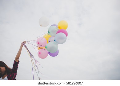 Woman with colorful balloons outside blue sky background.