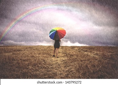 Woman with colorful umbrella in the rain for the field