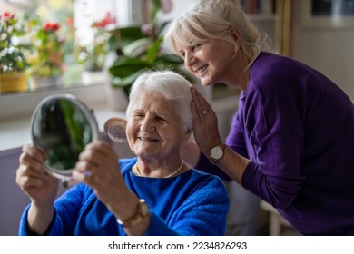 Woman combing hair of elderly mother  - Powered by Shutterstock