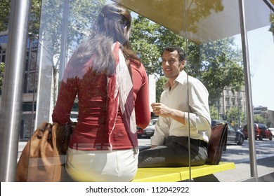 Woman communicating with man while sitting on bus stop