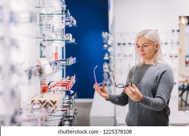 Woman Comparing Glasses At Optic Store. Eyewear Shopping, Correction Glasses.