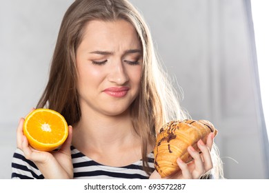 Woman comparing unhealthy cake and orange fruit